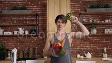 有魅力的素食男孩，一只手拿西兰花，另一只手拿蔬菜。